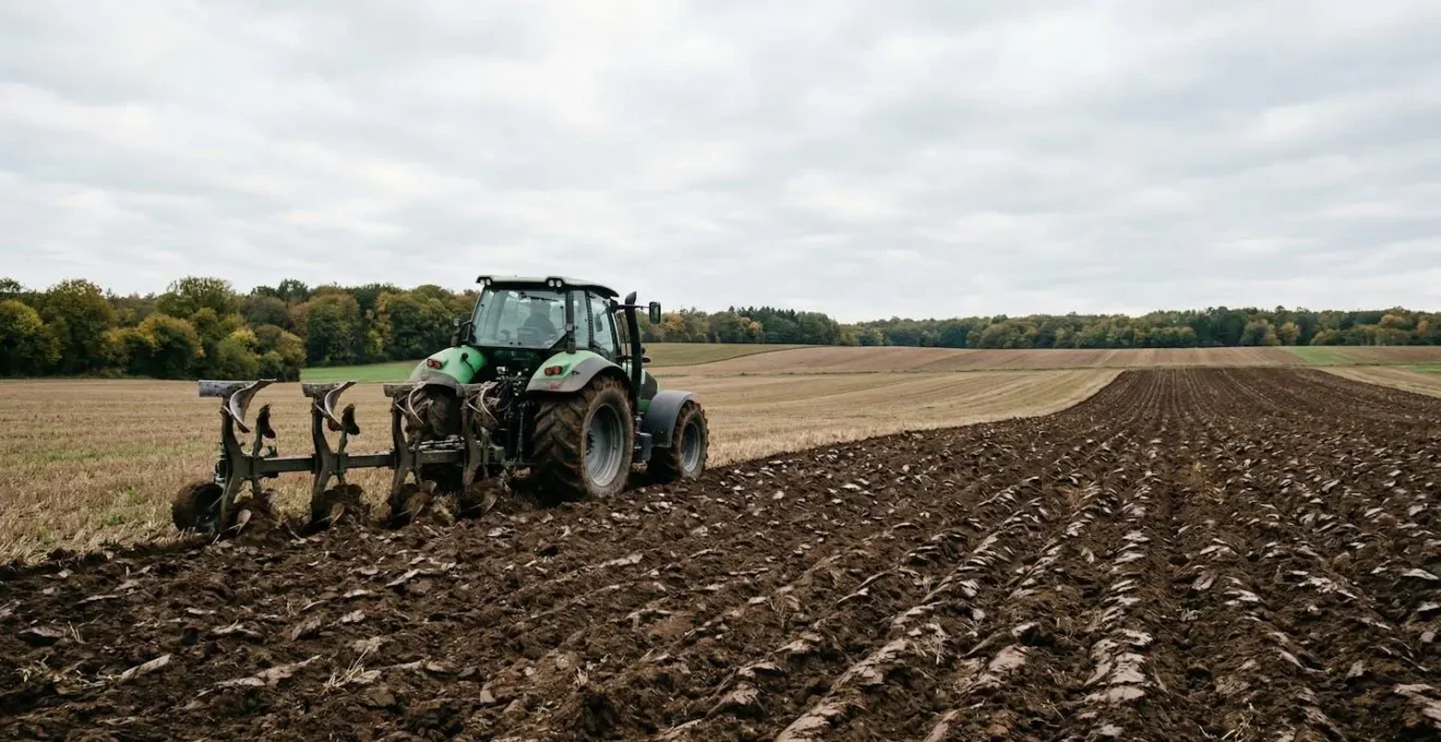 Moderner Traktor mit Pflug bei der Bodenbearbeitung auf deutschem Ackerland